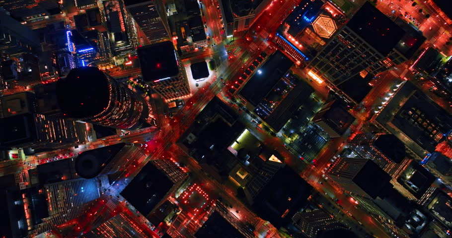 Well-lit streets and neighborhoods of San Francisco, California, USA at night. Drone footage over the rooftops of high-rises and skyscrapers.