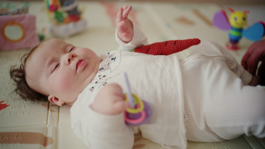 Cute baby lying on a mat playing with a soft hot pepper toy