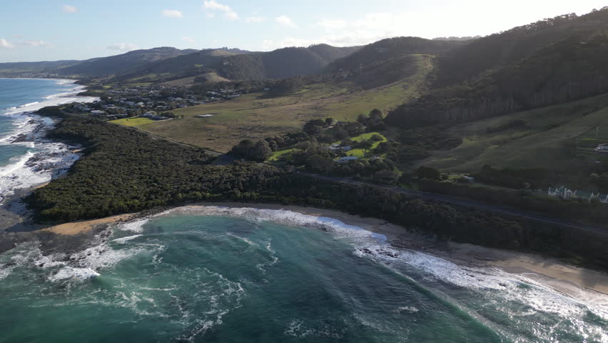 Aerial view Great Ocean Road Australia. Highway along the Southern Ocean surrounded by mountains, waves crashing on the rocky shore, beautiful nature landscape, travel and tourism.
