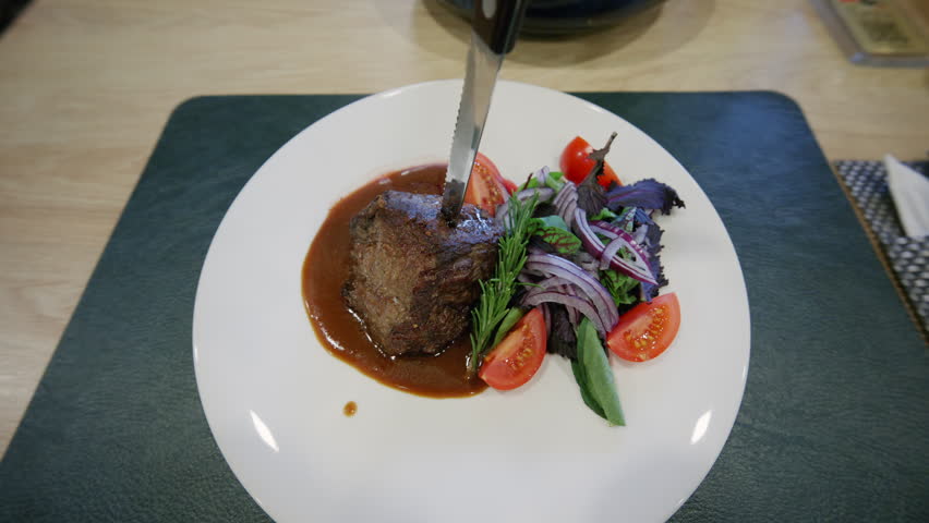 Close up of a gourmet meat dish served with sauce and fresh vegetables