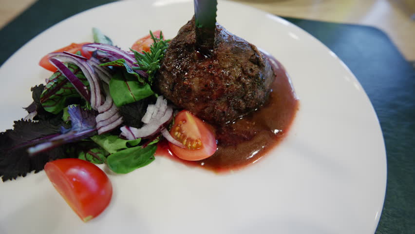 Close up of a gourmet meat dish served with sauce and fresh vegetables