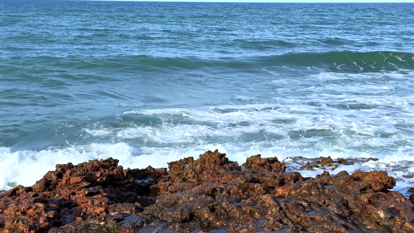 Ocean waves crashing on rocky shoreline with high spray