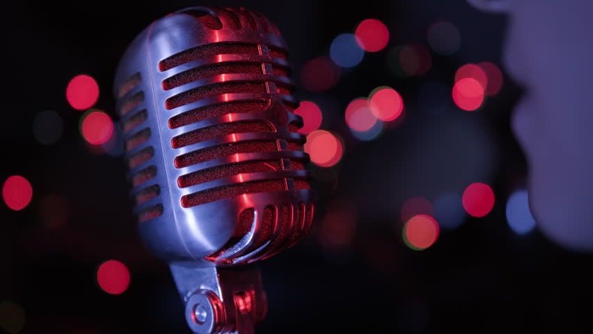 Singer singing into retro vintage microphone on stage in club close-up.