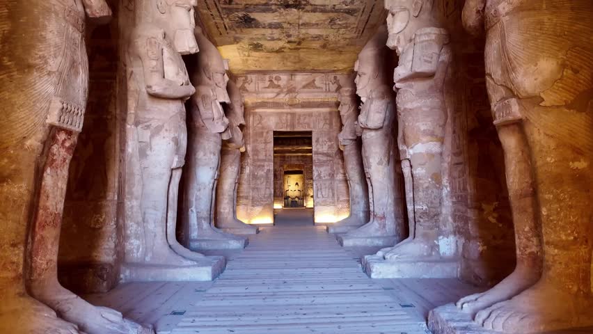 tilt up of Majestic interior view of the great temple of abu simbel, showing giant osirid statues of ramesses ii and the ancient painted ceiling