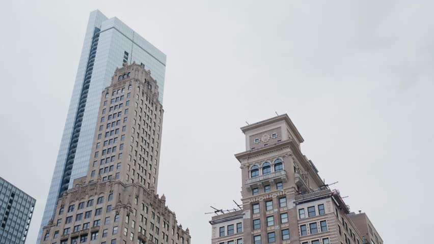 Historic skyscraper facades like Pittsfield Building and modern glass building exteriors contrast under overcast sky in downtown Chicago, Illinois