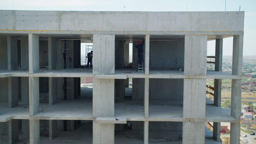 Workers inside unfinished concrete high rise structure