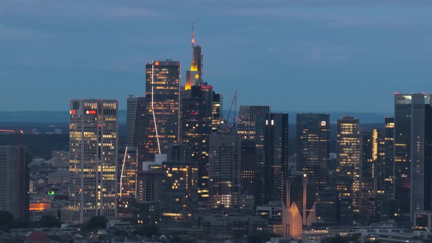 Frankfurt city skyline with glowing office windows illuminating metropolitan business district at dusk, finance, banking, global economy concepts