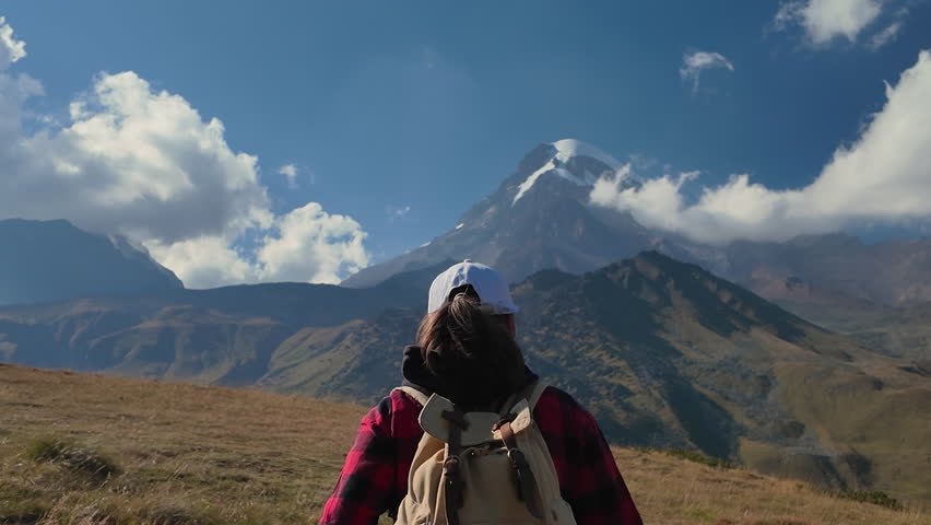 Hiker walking to Mount Kazbek with icy peak.