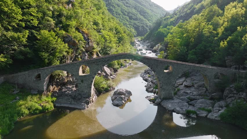 Devil Bridge ancient stone arch Arda river gorge Bulgaria aerial drone slow motion medieval landmark Rhodopes travel tourism green canyon Ardino heritage