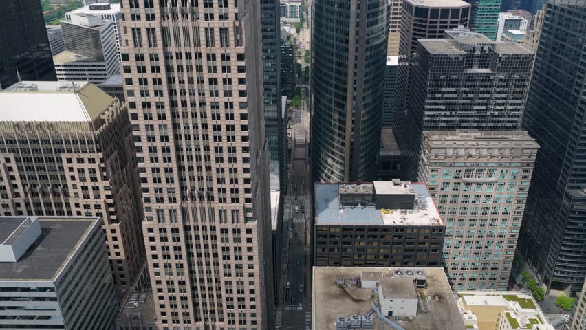 High altitude aerial descending over urban canyon of a street surrounded by skyscrapers and historical buildings in downtown Chicago