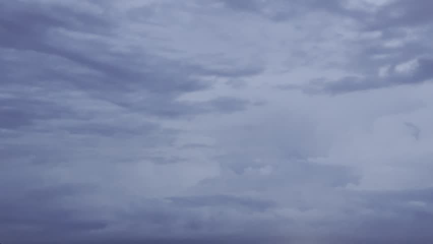 A short clip of a cloudy sky at twilight, with flashes of lightning briefly illuminating the dense cloud cover from within, capturing the dramatic energy of an approaching storm.