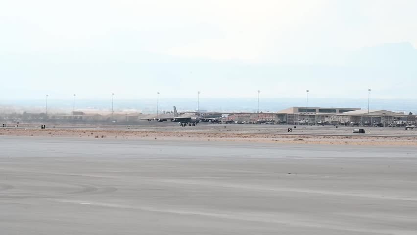 A United States Air Force B-52 Stratofortress strategic bomber aircraft taking off from a military air base runway in a desert environment, showcasing long-range strike capabilities and iconic Cold War-era aviation design.