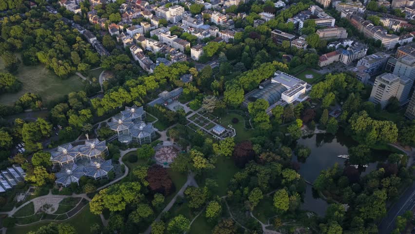 Frankfurt Palmengarten cityscape showing urban park with pond, Palmenhaus and botanical garden buildings surrounded by green trees and Westend district architecture