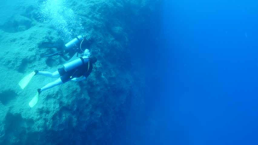 underwater scenery of big rocks topography scuba divers exploring