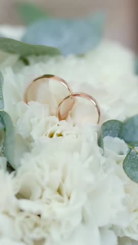 A bride with a wedding ring on her hand strokes and admires her wedding bouquet of flowers, close-up