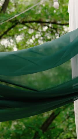 A romantic wedding arch made of white roses and green tulle before the bride and groom ceremony. Decor and floristry	