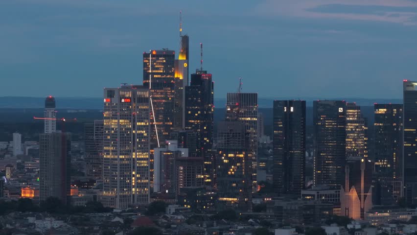 Frankfurt am Main skyline at night showing illuminated cityscape with modern skyscrapers and office buildings, aerial establishing shot of Germany