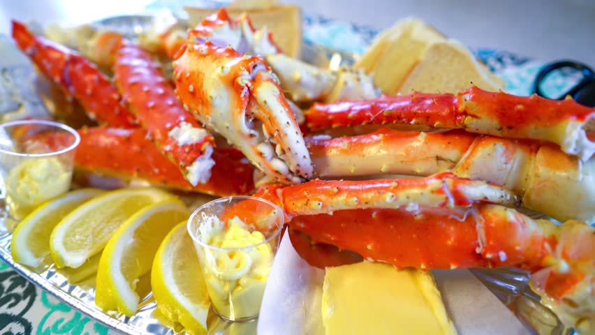 Steaming crab legs served with lemon and butter on a platter.