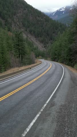 Winding Mountain Road Through Lush Forests with Distant Snow-Capped Peaks, British Columbia, Canada