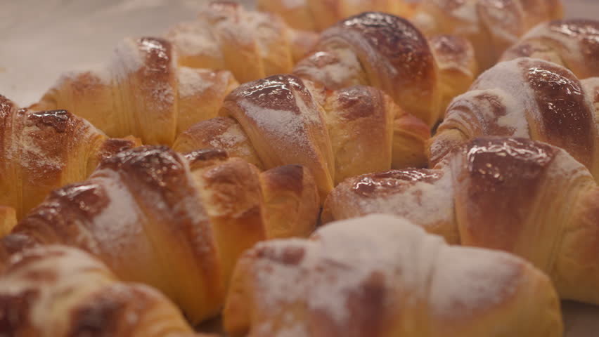 Freshly baked, golden croissants lined up for customers in a warm Parisian bakery. The sweet aroma fills the air, inviting all to enjoy a delightful treat.