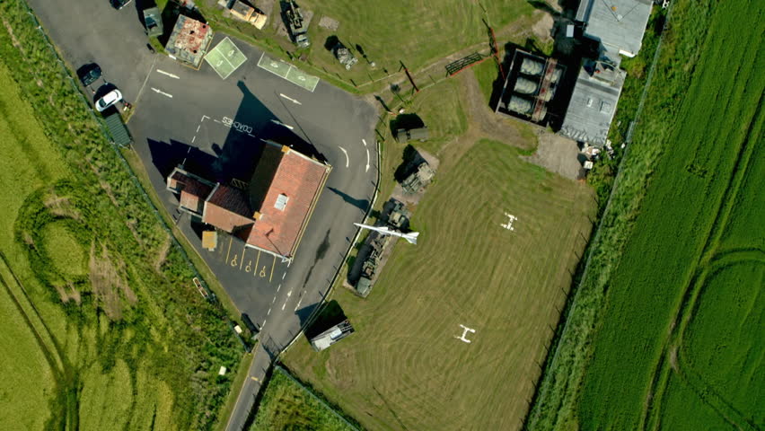 Top down aerial rotating shot of a military museum with armored vehicles, tanks, and an airplane