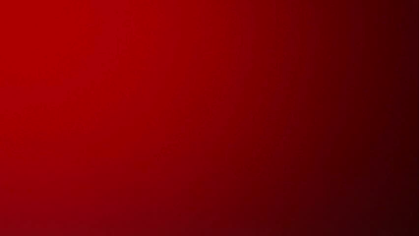 Large quantities of brass bullet shells and whole ammunition rounds falling and tumbling together against a solid red background in slow motion studio detail