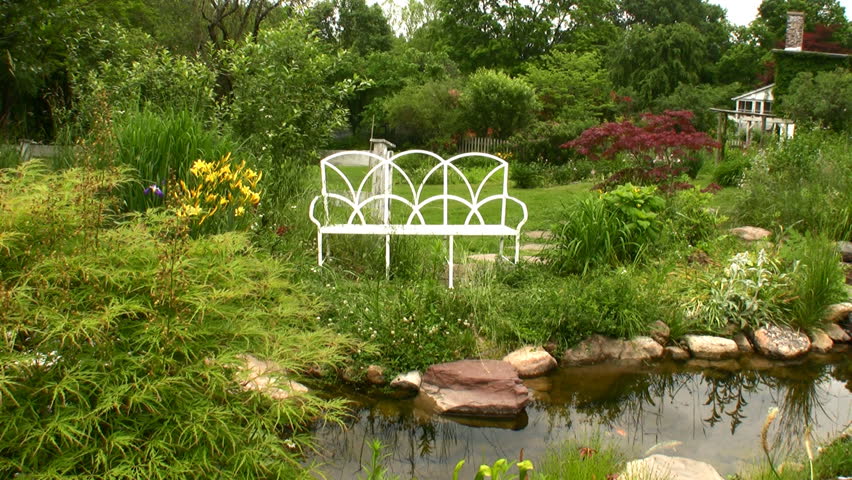 white garden bench next to a pond