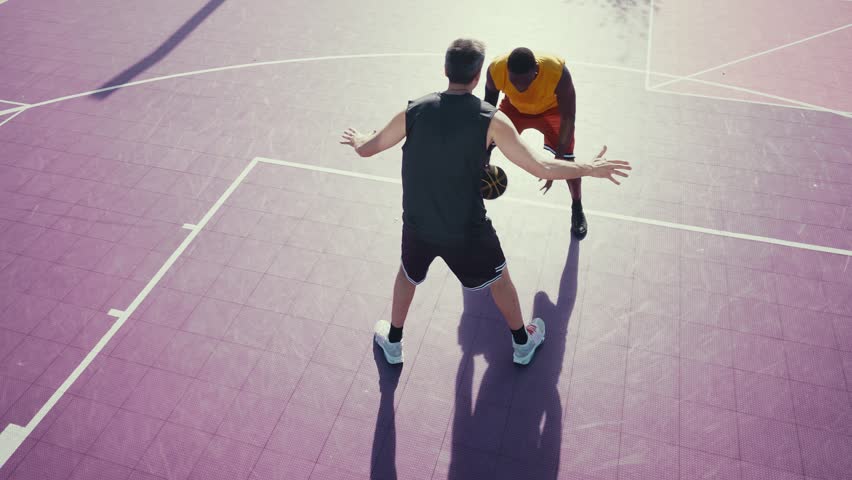 Players dunking basketball during competitive game on court