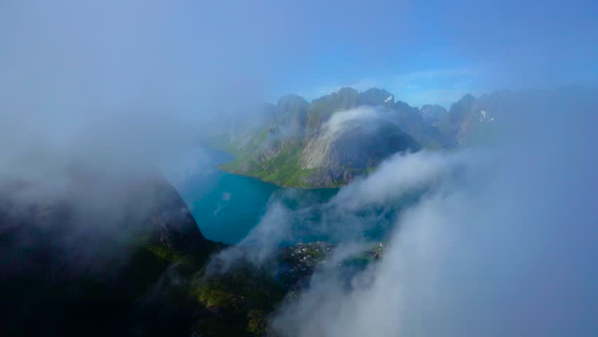 Dramatic drone flight over misty fjords and rocky peaks.