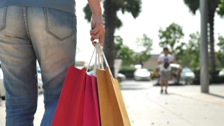 shopper Rare view of an american girl walking down the walking in the shopping mall alone in daytime. shopping bags walking in street downtown city