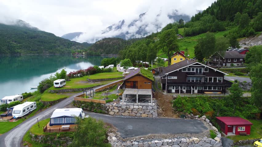 Aerial view of RV park, lake, mountains, cloudy sky, tranquil nature.
