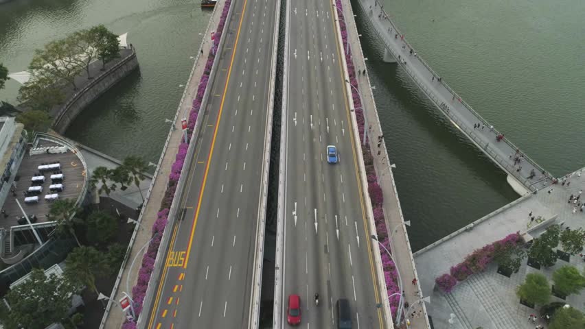 Aerial view captures bustling Singapore urban landscape. Cars navigate busy multi-lane highway bridge.