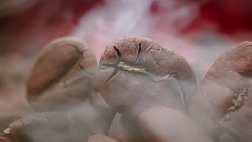 Roasted coffee beans with rising smoke in cinematic close up.