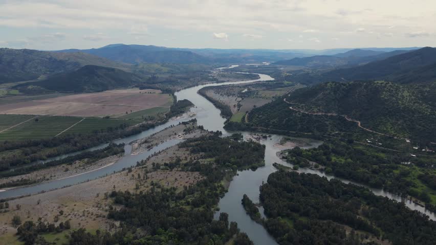 Wide drone view of the Rio Claro and Rio Maule meeting in Perales, Maule Region, Chile, with winding water, hills and rural farmland.