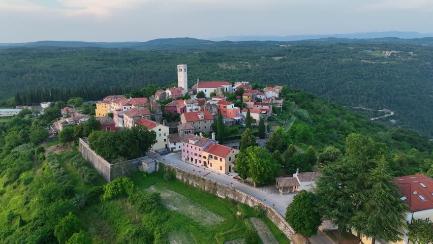 Cinematic aerial drone shot of Oprtalj hilltop medieval town in Istria Croatia during summer with historic stone houses, narrow streets, surrounding hills and authentic European scenery