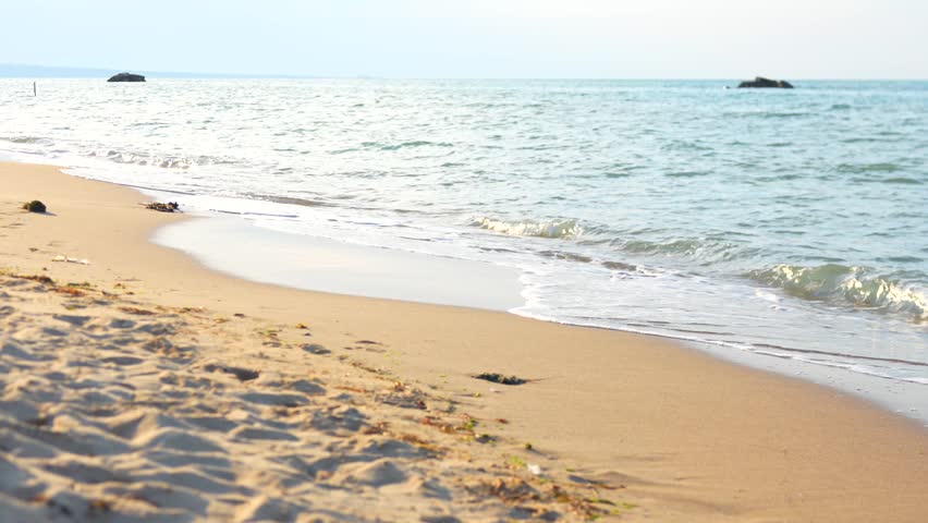 Gentle Sea Waves Rolling onto Sandy Beach Shoreline in Soft Daylight