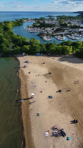 Cinematic aerial footage of the Scarborough Bluffs during golden hour in Toronto, Ontario, Canada. Drone view captures the iconic white cliffs, sandy shoreline, gentle waves of Lake Ontario, and warm sunset light illuminating the natural coastal landscape.