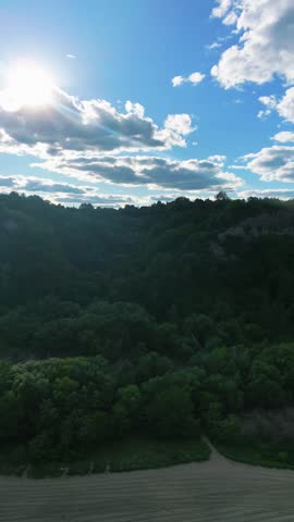 Cinematic aerial footage of the Scarborough Bluffs during golden hour in Toronto, Ontario, Canada. Drone view captures the iconic white cliffs, sandy shoreline, gentle waves of Lake Ontario, and warm sunset light illuminating the natural coastal landscape.