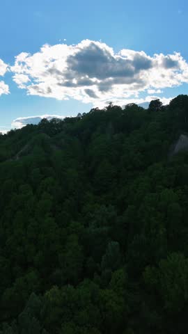Cinematic aerial footage of the Scarborough Bluffs during golden hour in Toronto, Ontario, Canada. Drone view captures the iconic white cliffs, sandy shoreline, gentle waves of Lake Ontario, and warm sunset light illuminating the natural coastal landscape.