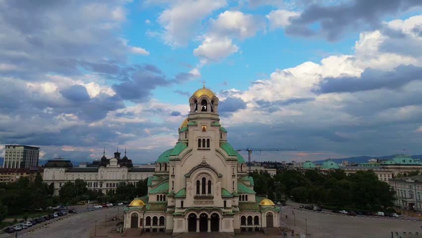 Medium aerial tracking shot backwards revealing the majestic structure of Alexander Nevsky Cathedral under a dramatic cloudy sky in Sofia Bulgaria capital city
