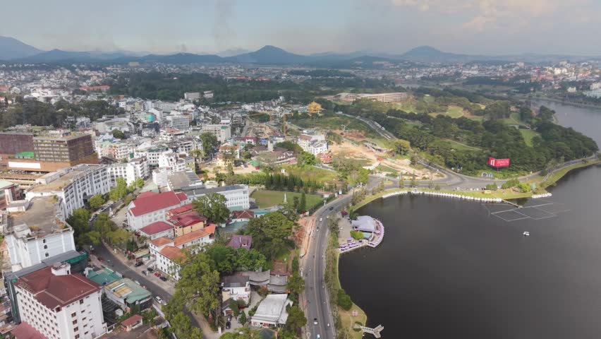 Vietnam, Da Lat Aerial View Da Lat Lakeshore Curve With Mountain Backdrop, Winding Road Along Waterfront, Boats And Green Hills, Distant Peaks Under Soft Haze. Local Tour Guide Leading