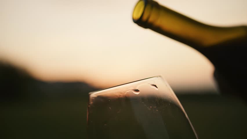 As the sun dips behind the hills, a hand elegantly pours rich red wine into a glass, capturing the essence of an unforgettable evening at the winery.