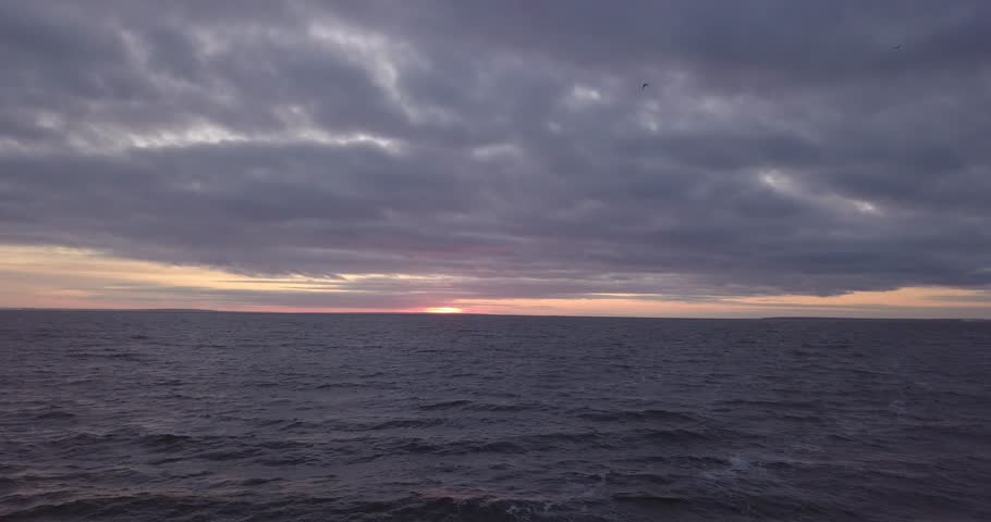 Flying over a choppy river in the evening at sunset in cloudy weather