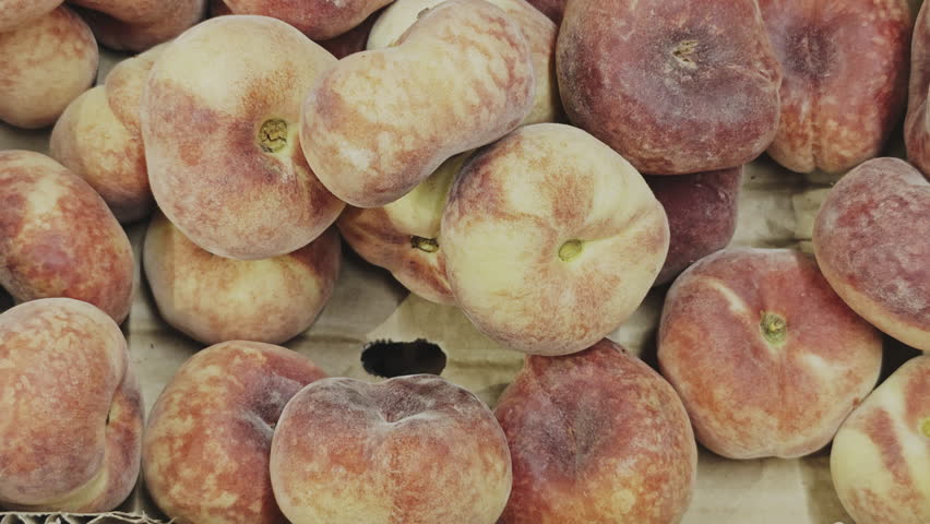 Fresh donut peaches, also known as Saturn peaches, for sale at a local fruit market, close up view from above