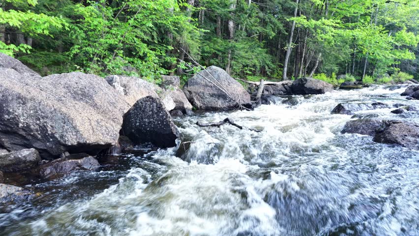 Backing out from under the historic stone arch bridge in Stoddard, NH on a sunny spring evening, featuring a rocky shore, rapids and white water 
