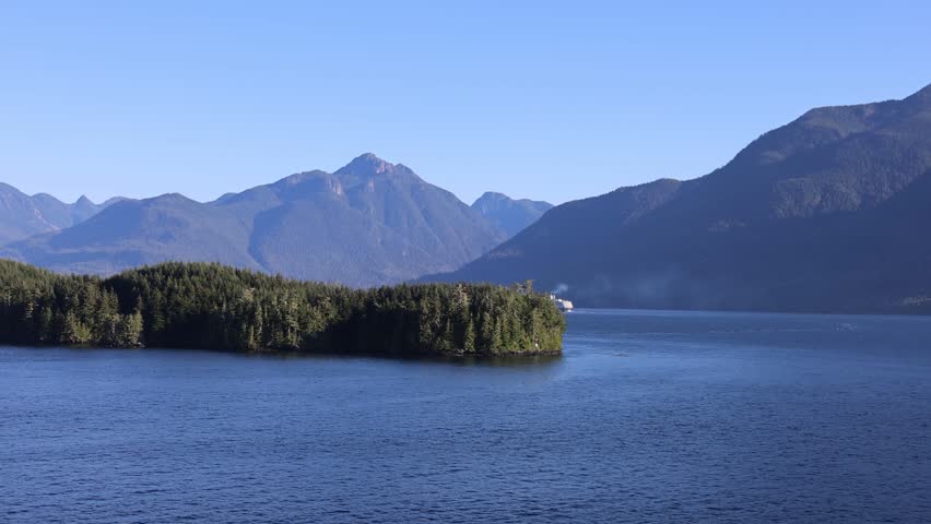 Aerial view of the Inside Passage with forested islands and majestic mountains under a clear blue sky in Ketchikan Gateway Borough, Alaska, United States.