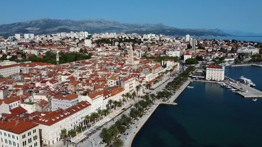 Aerial view of the historic old town with red rooftops, the Saint Domnius bell tower, and people walking along the Riva promenade in Split, Split-Dalmatia County, Croatia.