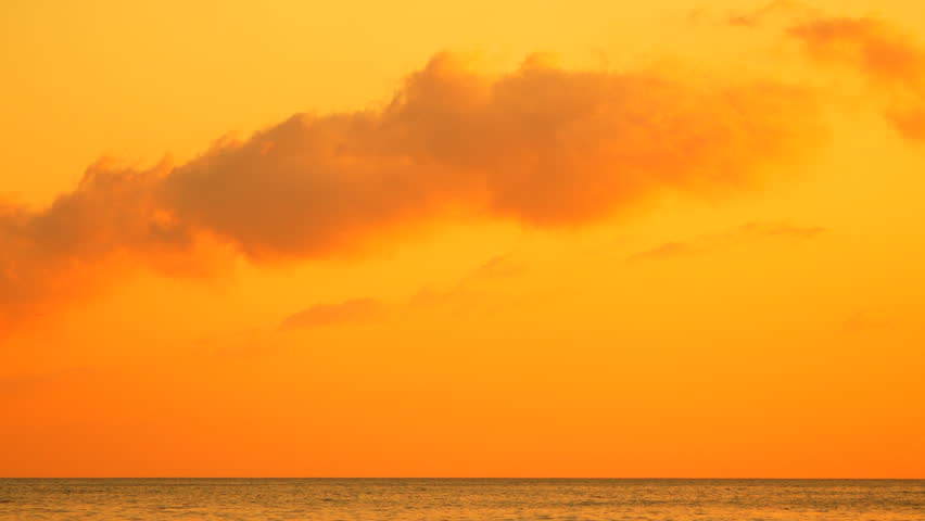 Sunset Ocean Clouds with vibrant orange sky reflecting over the calm sea at dusk during a peaceful tropical evening