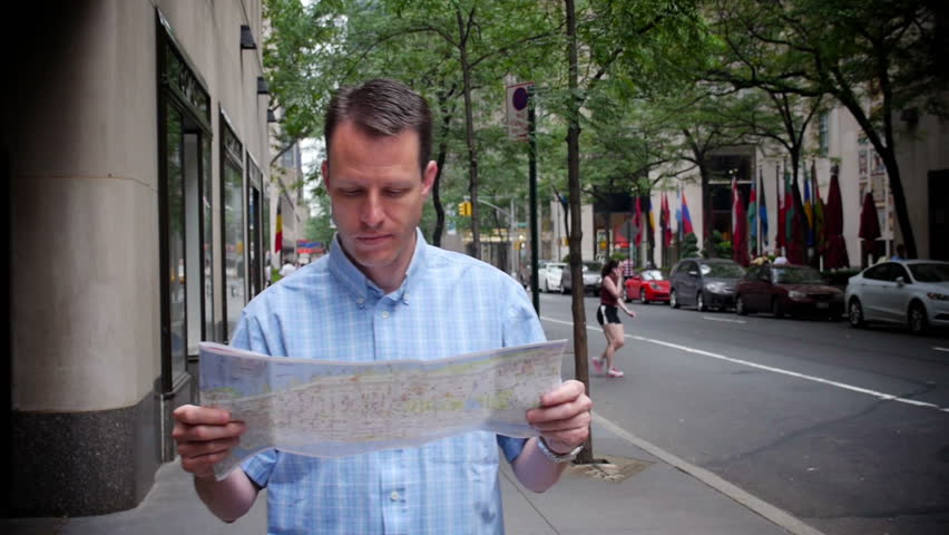 A man in New York City looks at a map while walking.