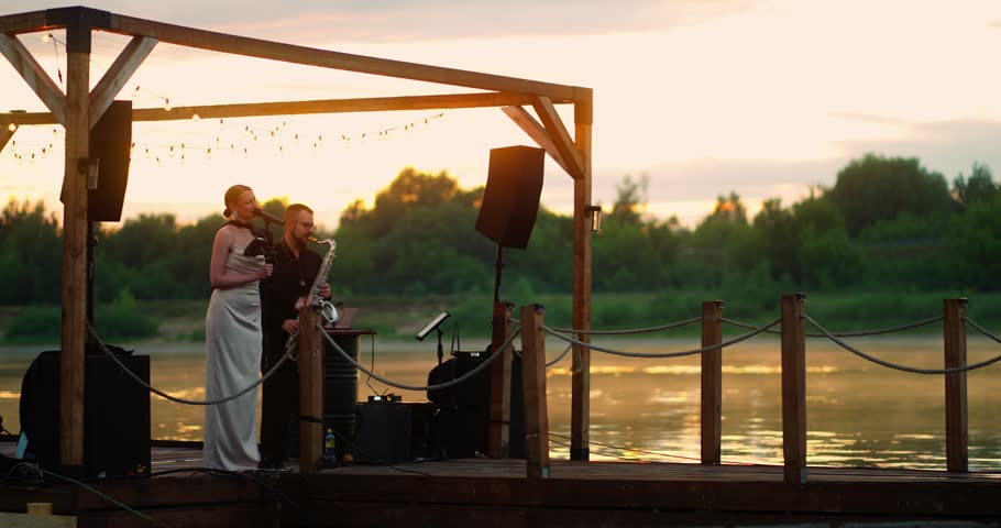 Sunset duet on a wooden lakeside pier under string lights